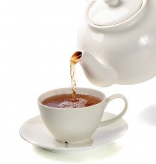 Tea being poured into tea cup isolated on a white background
